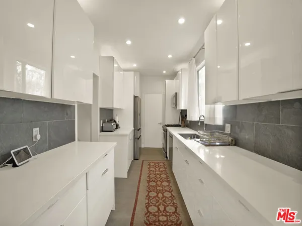 a large white kitchen with a sink and cabinets