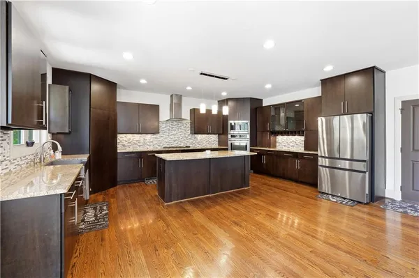 a large kitchen with stainless steel appliances kitchen island granite countertop a refrigerator and a sink