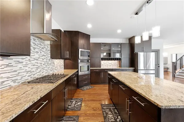 a large kitchen with granite countertop counter top space a sink stainless steel appliances and cabinets