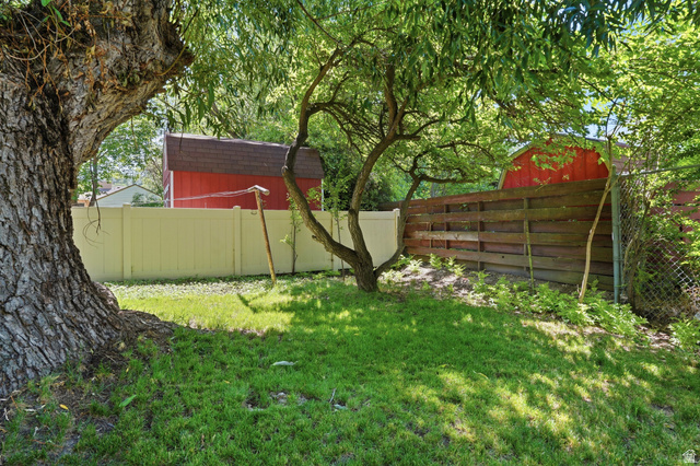 270 East 700 North Logan, UT 84321 - Photo 36 of 42 Expansive green lawn framed by mature trees, featuring a light-colored privacy fence and a dark wood fence
