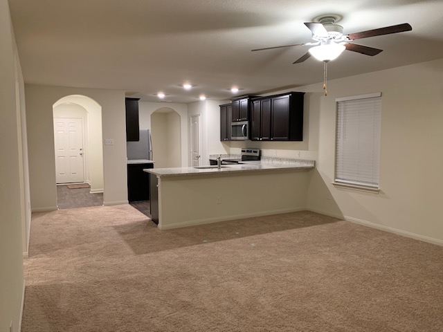 140 Allington Circle Jarrell, TX 76537 - Photo 19 of 23 Kitchen with dark cabinetry, arched walkways, light colored carpet, a peninsula, and recessed lighting