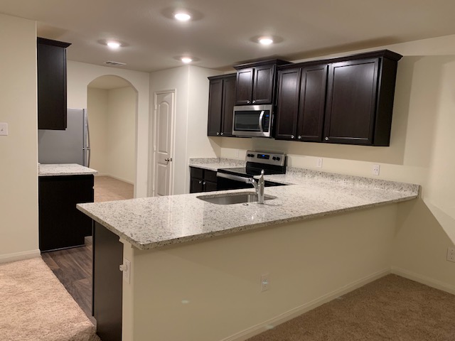 140 Allington Circle Jarrell, TX 76537 - Photo 21 of 23 Kitchen with arched walkways, light stone countertops, a peninsula, stainless steel appliances, and recessed lighting