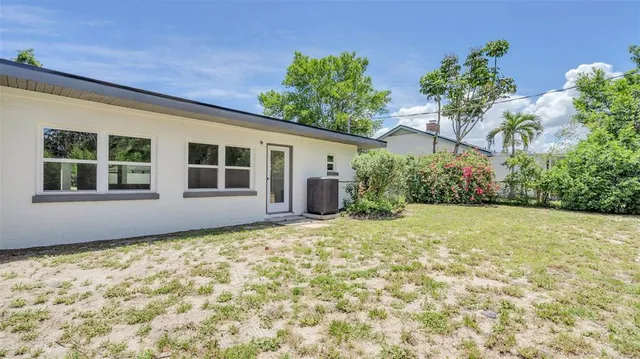 a view of an empty room with wooden floor and a kitchen