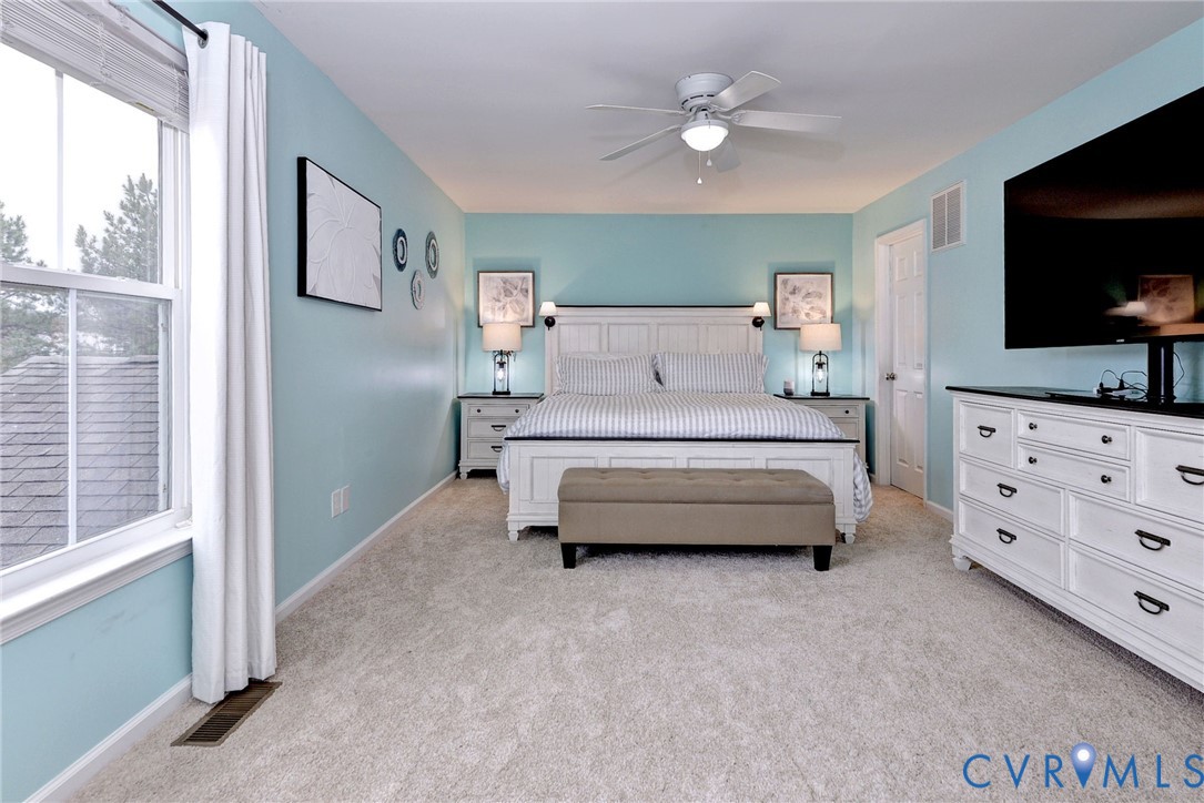 8428 Sheldon Branch Place Toano, VA 23168 - Photo 22 of 46 a bedroom with a bed a mirror and a flat tv screen on dresser