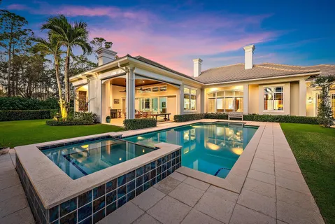a view of a white house with a big yard and palm trees