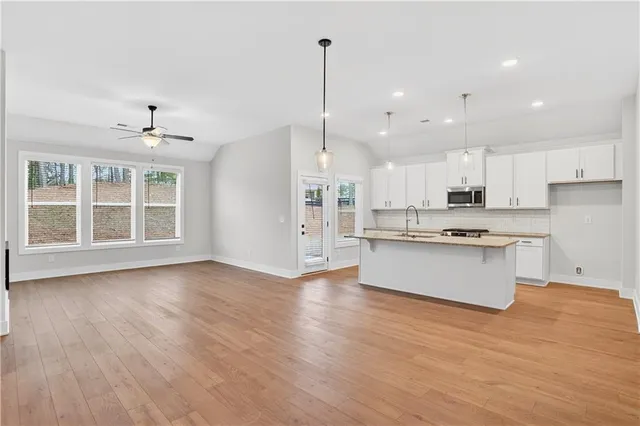 a kitchen with granite countertop kitchen island stainless steel appliances a sink stove and cabinets