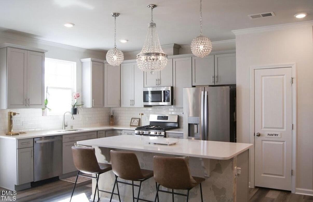 5006 Tura Street Raleigh, NC 27610 - Photo 11 of 32 a kitchen with stainless steel appliances a table chairs refrigerator and cabinets