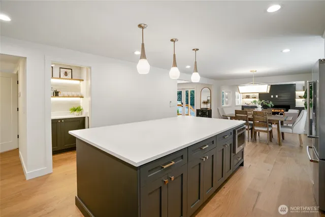 a large kitchen with kitchen island a sink dishwasher a stove a dining table and chairs with wooden floor