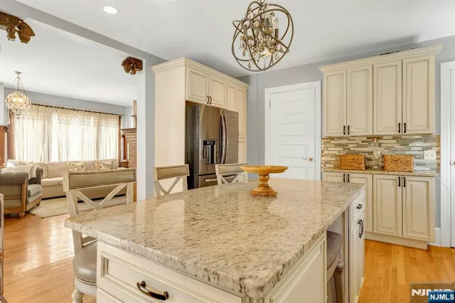 a view of a kitchen with kitchen island granite countertop wooden floor and a view of living room