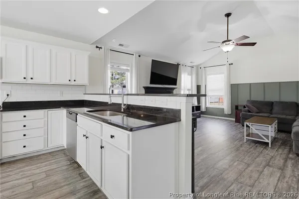 a kitchen with granite countertop a sink and white cabinets with wooden floor