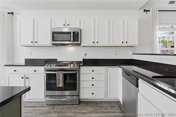 a kitchen with white cabinets and appliances