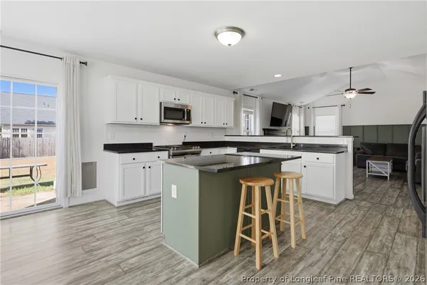 a kitchen with stainless steel appliances granite countertop a stove top oven a sink dishwasher and a refrigerator with wooden floor