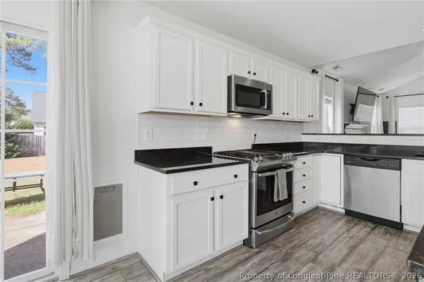 a kitchen with stainless steel appliances granite countertop a stove a sink and a microwave