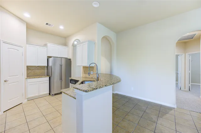 a kitchen with a refrigerator a oven and white cabinets