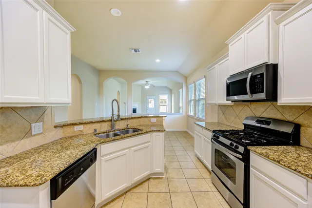 a kitchen with stainless steel appliances granite countertop a sink stove and cabinets