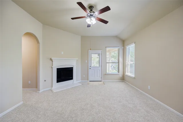an empty room with windows and fireplace