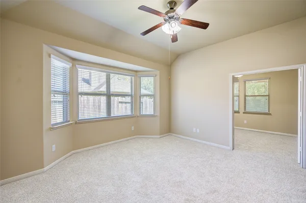 an empty room with chandelier fan and windows
