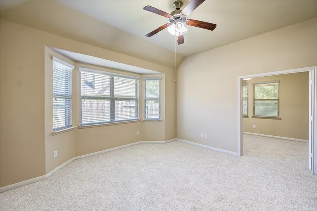 an empty room with chandelier fan and windows