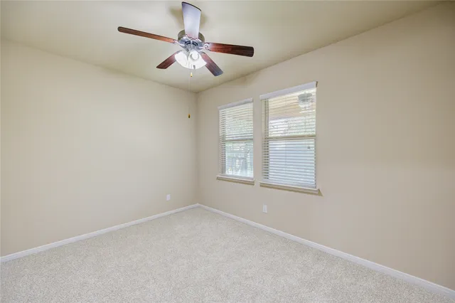 en empty room with windows and chandelier fan
