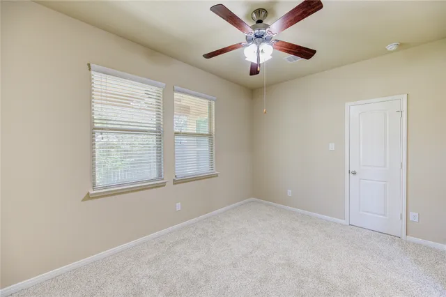 an empty room with chandelier fan and windows