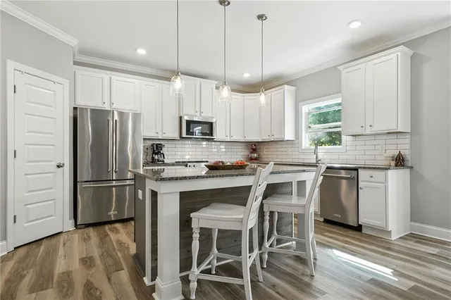 a kitchen with kitchen island white cabinets and stainless steel appliances