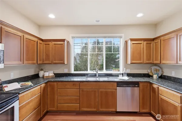 a kitchen with granite countertop wooden cabinets a sink and a window