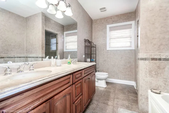 a bathroom with a granite countertop sink a toilet and a mirror