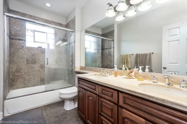 a bathroom with a granite countertop sink a toilet a mirror and shower