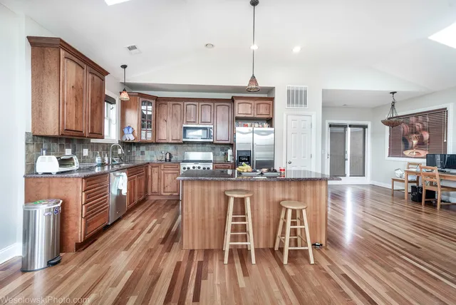 a large kitchen with stainless steel appliances microwave stove refrigerator and wooden floor