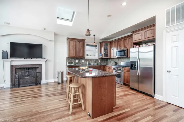 a kitchen with stainless steel appliances granite countertop a stove top oven a refrigerator and a kitchen island