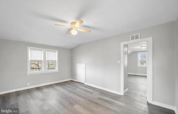 a view of an empty room with a window and wooden floor