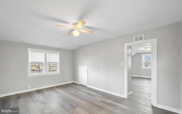 an empty room with windows and a chandelier fan