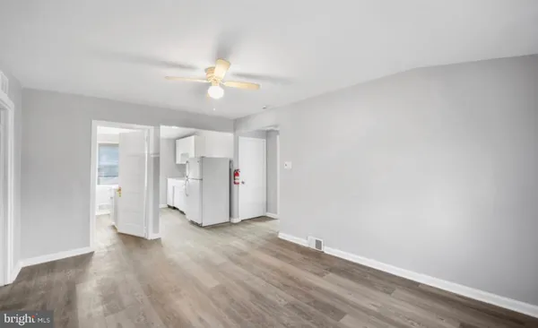 an empty room with wooden floor and ceiling fan