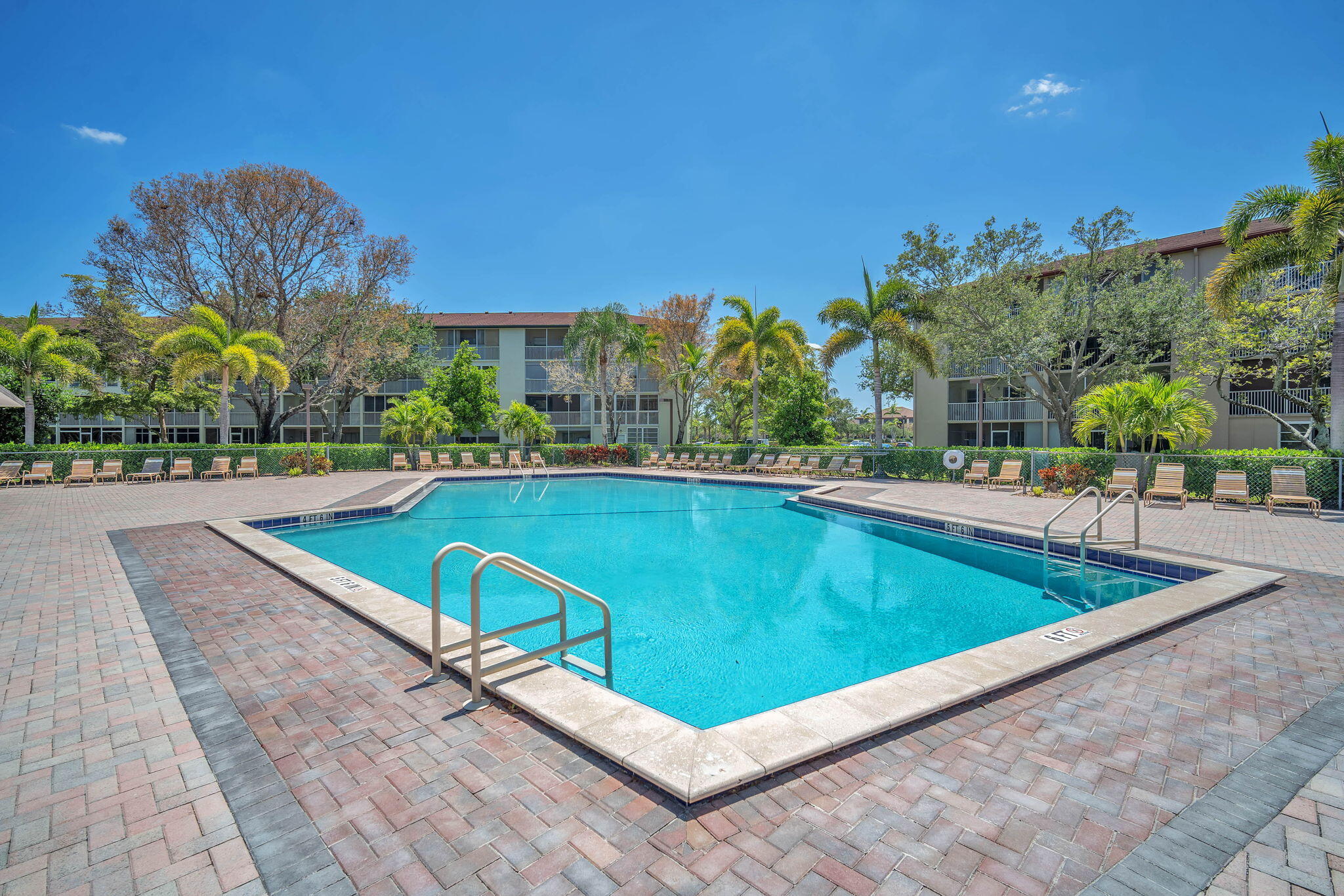 801 Southwest 133rd Terrace, Unit 317K Pembroke Pines, FL 33027 - Photo 12 of 13 a view of a swimming pool with a bench and trees in the background
