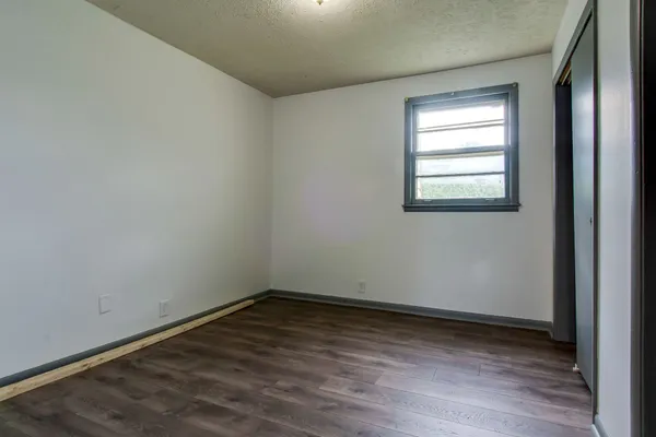 a view of an empty room with wooden floor and closet