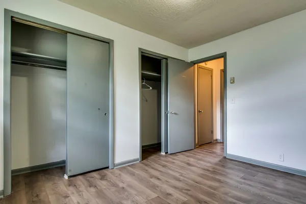 a view of an empty room with wooden floor and closet
