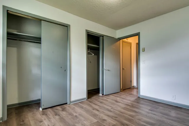 a view of an empty room with wooden floor and closet