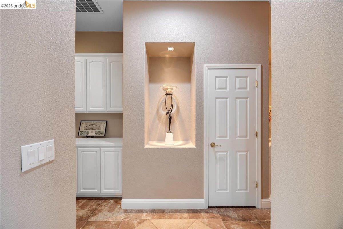 158 Rock Ridge Lane Copperopolis, CA 95228 - Photo 28 of 72 Hallway featuring a built-in display niche with recessed lighting, a six-panel interior door with brass hardware, and ceramic tile flooring