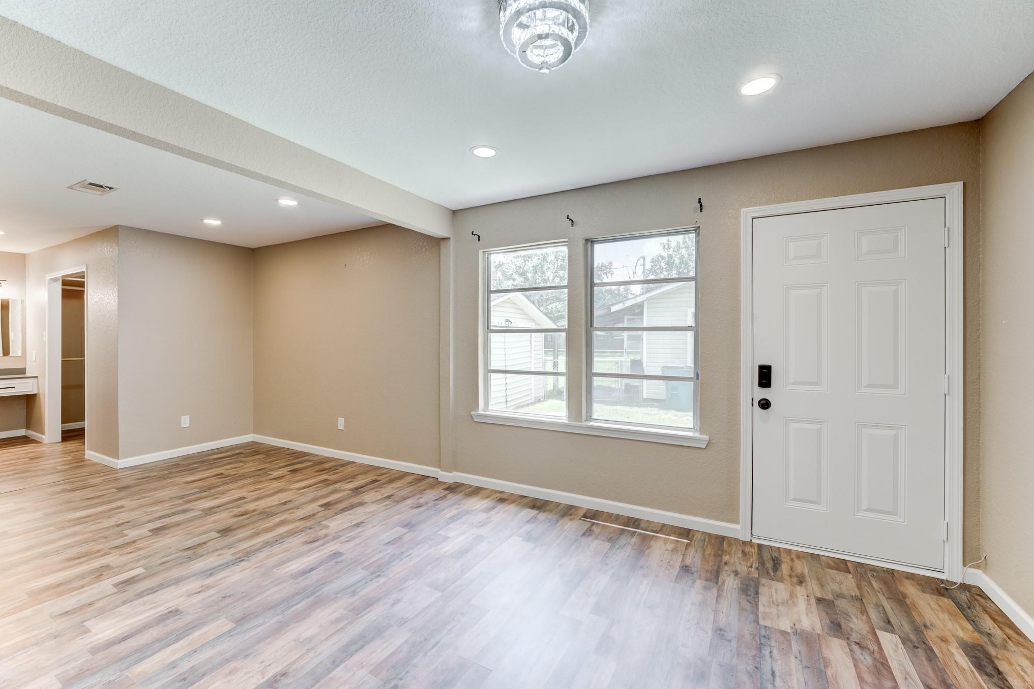 305 Yaupon Street Sweeny, TX 77480 - Photo 22 of 22 This bright room features wood-style flooring, recessed lighting, and a modern light fixture. It includes large windows and a door leading outside, with neutral-toned walls for a fresh, airy feel. Ideal for a living or multifunctional space.
