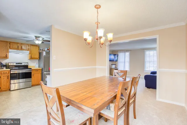 a dining room with wooden floor a chandelier a wooden table and chairs