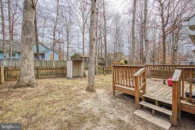 a view of backyard with deck and wooden fence