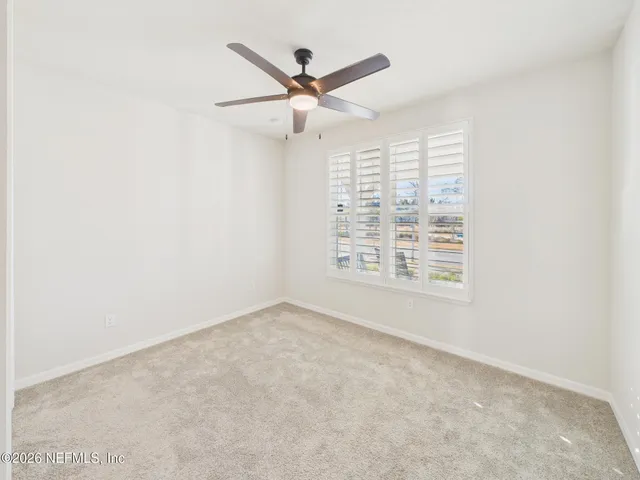 an empty room with a fan & a ceiling fan