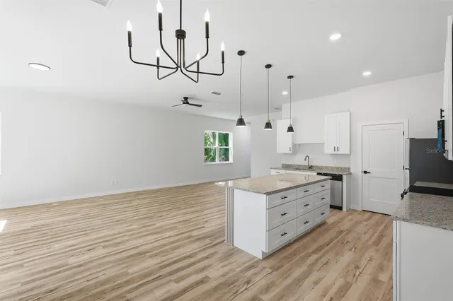 a kitchen with stainless steel appliances granite countertop white cabinets and a refrigerator a stove top oven