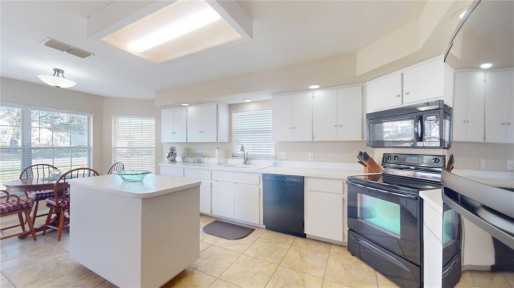 4427 North Bacall Loop Beverly Hills, FL 34465 - Photo 11 of 41 a kitchen with stainless steel appliances granite countertop a stove top oven a sink dishwasher a dining table and chairs with wooden floor