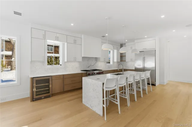 a kitchen with stainless steel appliances granite countertop a stove a sink a refrigerator and white cabinets with wooden floor