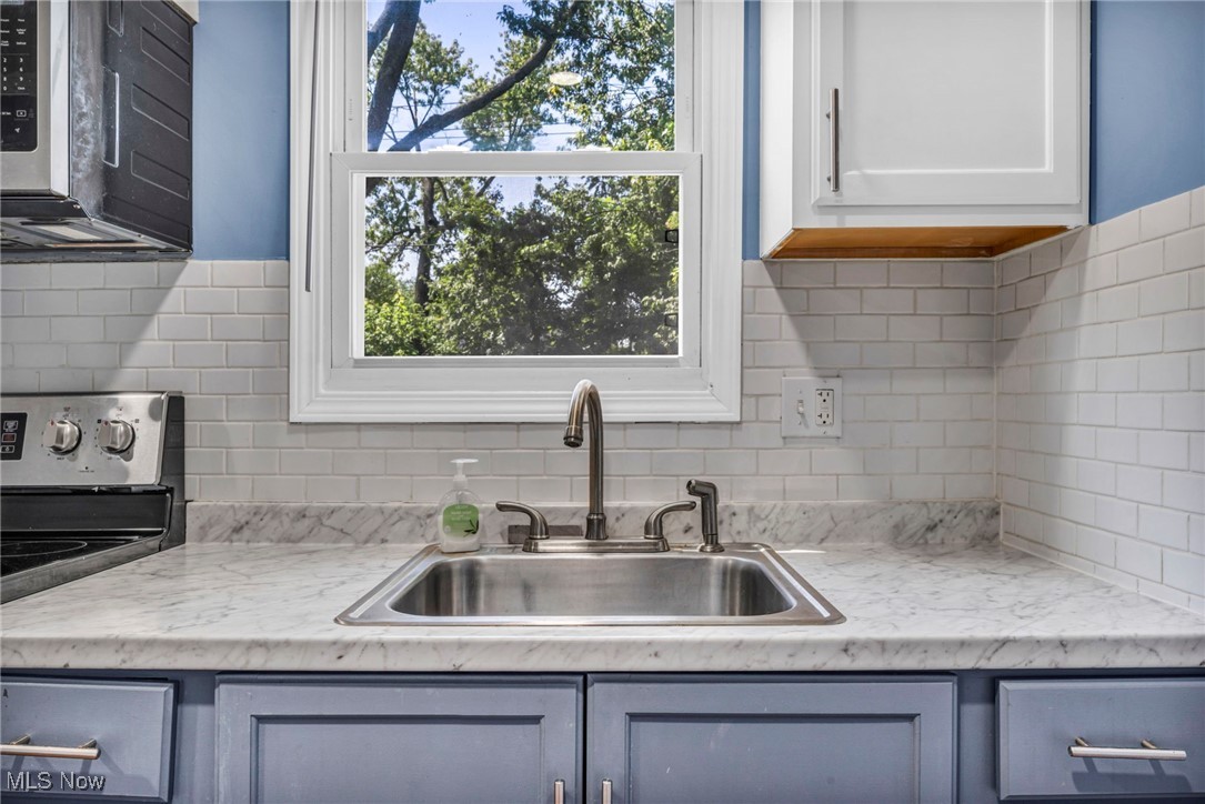 21100 Watson Road Maple Heights, OH 44137 - Photo 11 of 37 Kitchen with stainless steel microwave, range, light countertops, backsplash, and plenty of natural light