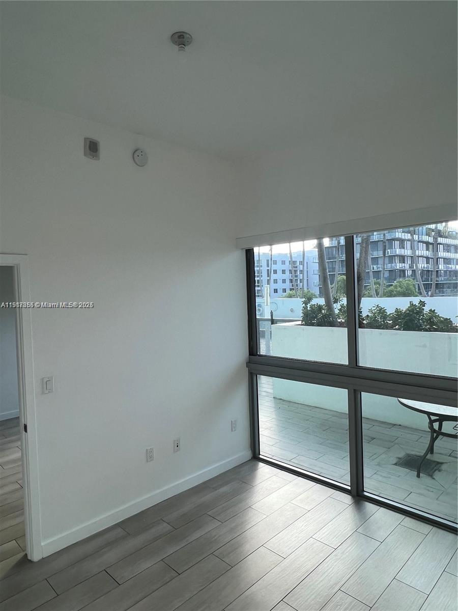 1600 Southwest 1st Avenue, Unit 412 Miami, FL 33129 - Photo 4 of 12 an empty room with wooden floor and windows
