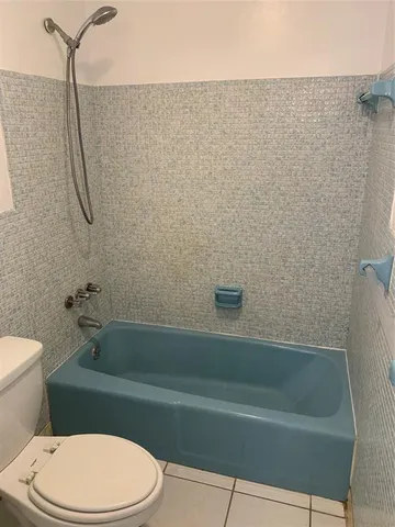 a bathroom with a white toilet and bathtub