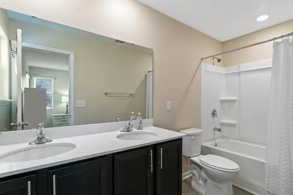 a bathroom with a double vanity sink toilet mirror and shower