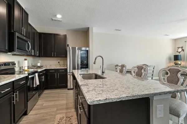 a kitchen with granite countertop kitchen island stainless steel appliances a sink stove top oven and refrigerator